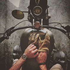 a man sitting on top of a motorcycle holding his hands up to the front wheel