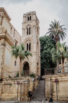 an old building with stairs leading up to it and palm trees in the foreground