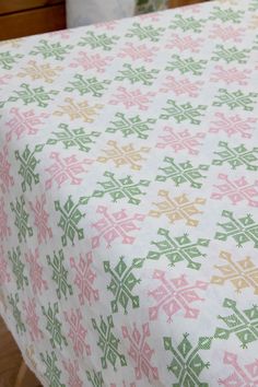 a close up of a table cloth on a wooden table with a vase in the background