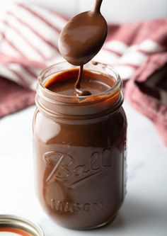 a spoon full of melted chocolate on top of a jar