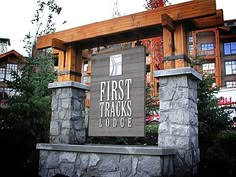 a sign for the first thanks lodge in front of a building with trees and bushes