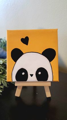 a small canvas with a panda face painted on it