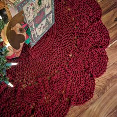 a red crocheted doily with a teddy bear on it next to a christmas tree