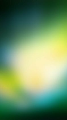 an abstract blurry background in green, yellow and blue with some white on the top