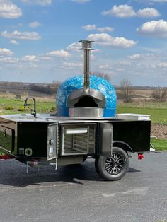 an outdoor cooking area on the back of a trailer with a blue ball in the background