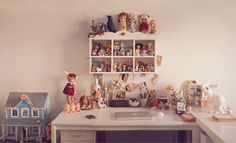 a white desk topped with lots of figurines next to a shelf filled with toys