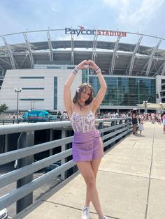 a woman posing in front of a stadium with her hands above her head and the words paycoff stadium on it