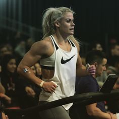 a woman is running on a treadmill in front of a large group of people