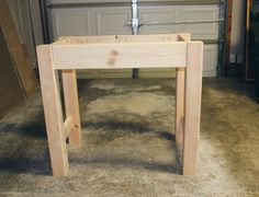 a wooden table sitting on top of a floor next to a garage door in front of a garage