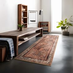 a living room with a large rug and wooden shelves on the wall next to it