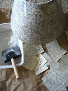 some pieces of paper and a hammer are on the ground next to a bowl with newspaper