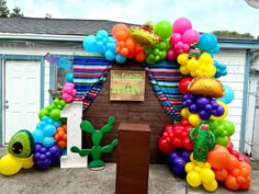 a bunch of balloons that are in the shape of animals and cactuses on a table