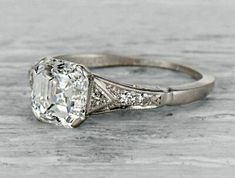 an old - fashioned engagement ring with a cushion cut diamond in the center and pave set shoulders