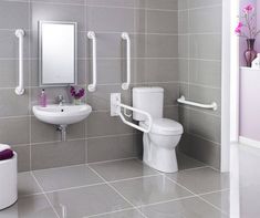 a white toilet sitting next to a sink in a bathroom under a mirror and towel dispenser