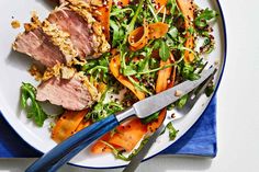 a white plate topped with meat and veggies on top of a blue cloth