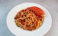 a white plate topped with spaghetti and lobster