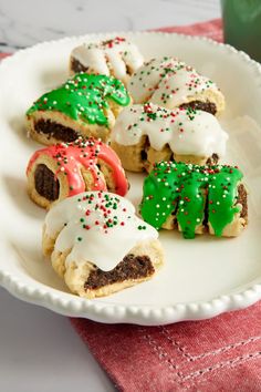 some cookies are on a white plate with green and red sprinkles in the shape of christmas trees