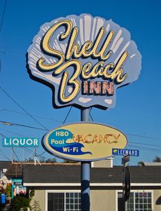 a sign for shell beach inn in front of a building with many signs on it