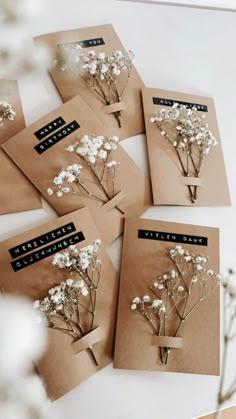 six small cards with flowers on them sitting on a table next to a vase filled with baby's breath