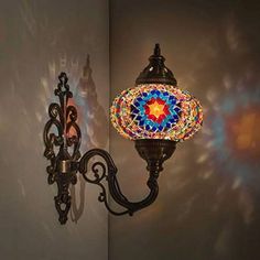 a wall light with a colorful mosaic glass shade on it's arm and back