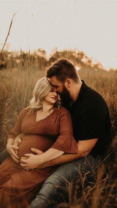 a pregnant couple cuddling in tall grass