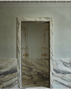 an open door leading to a bathroom with marble walls and flooring on either side