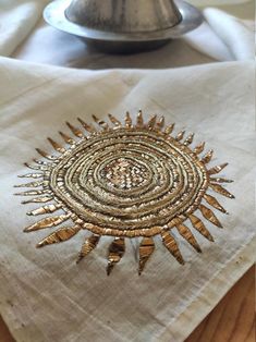 a white napkin with gold designs on it and a silver plate in the back ground