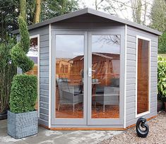 a small garden shed with glass doors and patio furniture