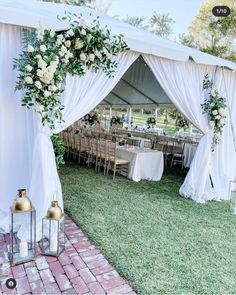 an outdoor wedding tent set up with white flowers and greenery