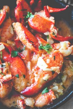 a skillet filled with cooked lobsters and rice, garnished with parsley