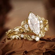 a gold ring with an oval cut diamond surrounded by leaves