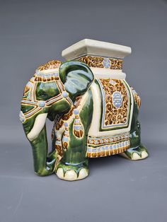 an elephant figurine sitting on top of a gray floor next to a vase