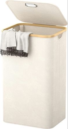 a white laundry hamper with two towels hanging from it's sides and a black handle