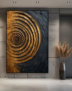 an abstract painting in gold and black on a wall next to a vase with dry grass