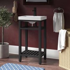 a white sink sitting under a mirror next to a potted plant and towel rack