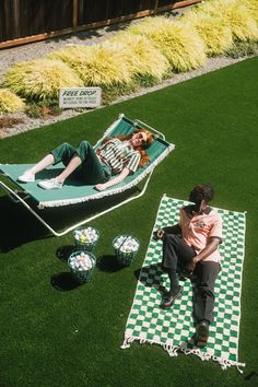 a woman laying on top of a green and white checkered rug next to a lawn