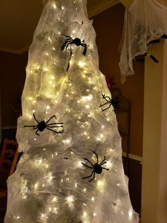 a white christmas tree with spider decorations on it