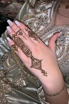 a woman's hands with hennap on her left hand and gold jewelry