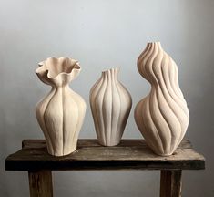 three white vases sitting on top of a wooden table