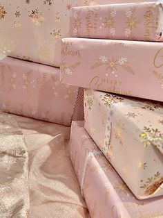 pink wrapping paper stacked on top of each other with snowflakes and gold lettering