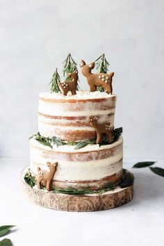 a three tiered cake decorated with deer and pine trees