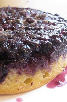 a close up of a doughnut with blueberry topping on a white plate next to a cup of coffee