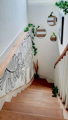 a stair case with plants on the wall and pictures hanging on the wall behind it