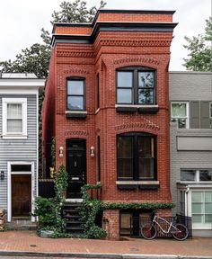 a red brick house with ivy growing on it's front and side windows, next to a bicycle parked in front