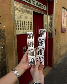 two people holding up photos in front of a red door with the words automatica on it