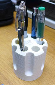 a pen holder with pens and pencils in it