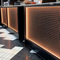 an empty restaurant with tiled flooring and counter tops, along with lights on the wall