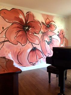 a piano sitting in front of a wall with flowers painted on it's side