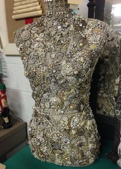 a mannequin with lots of buttons on it's back and sides, sitting in front of a mirror