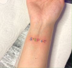 a woman's wrist with the word step out written on it in cursive font